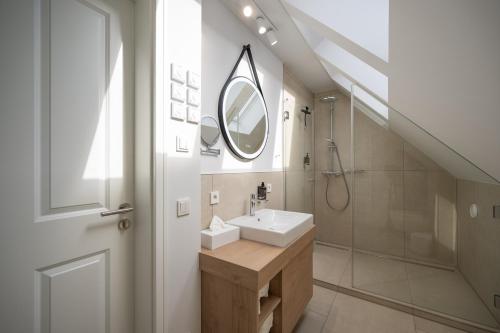 a bathroom with a sink and a shower and a mirror at Markt22 - Exklusive Stadtapartments in Lingen