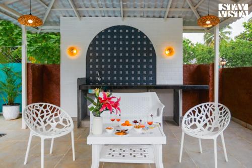 two chairs and a table with food on a patio at Belas Palmeiras by VEO - Part of StayVista with Pool & Bonfire in Alibaug