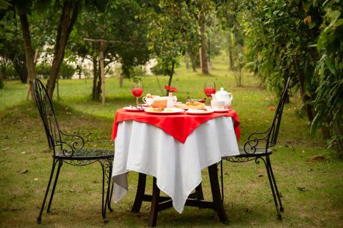 a table with a red and white table cloth and two chairs at Lumbini Zambala Hotel in Lumbini