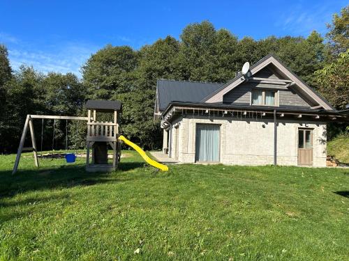 a house with a playground and a yellow frisbee in the yard at Wellness chata pod Orechom in Dolná Lehota