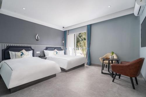 a bedroom with two beds and a chair at Sanya Yalong Bay Zhenghe Jingmei Hostel - Free Public Kitchen in Sanya