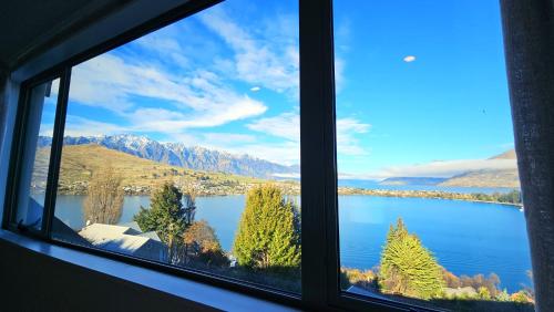 a window with a view of a lake and mountains at Panoramic, 180 Degree Lake and Mountain Views from Every Room! Central Queenstown in Queenstown