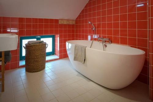 a red tiled bathroom with a tub and a sink at Chez Marie-Jeanne, City of Electricians in Bruay-la-Buissiere