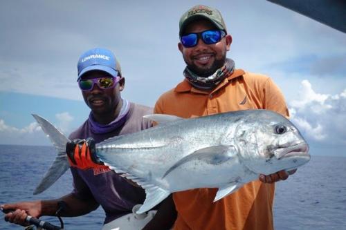 two men holding a silver fish in their hands at mafiakivulinilodge in Utende