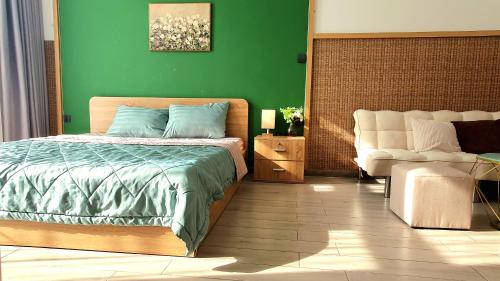 a green bedroom with a bed and a chair at Andi Homestay-Vinhomes Grand Park in Gò Công
