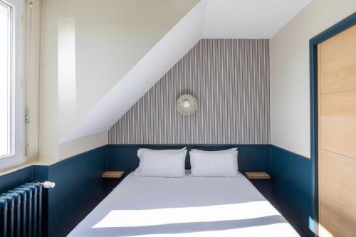 a bed with two pillows in a room at Hôtel BelleVue in Bréhat