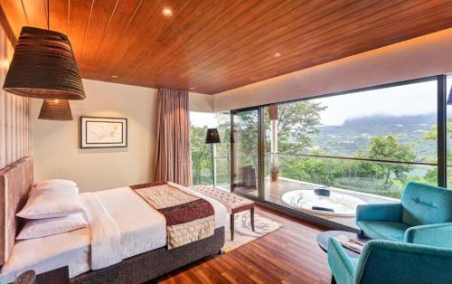a bedroom with a bed and a large window at Aamby Valley City in Lonavala