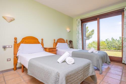two beds in a room with a window at Can Toni Gat in Bunyola