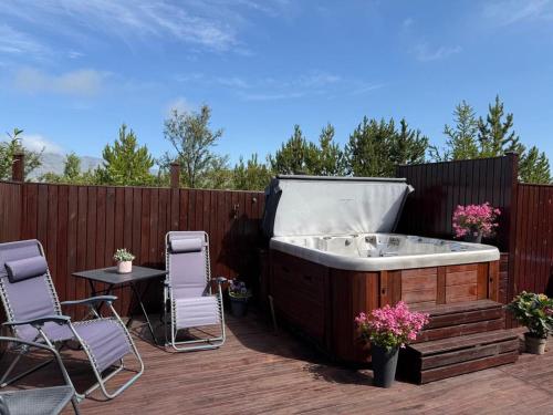 a hot tub on a deck with chairs and a table at Charming Private Home with Hot Tub and Esja Mountain View in Mosfellsbær