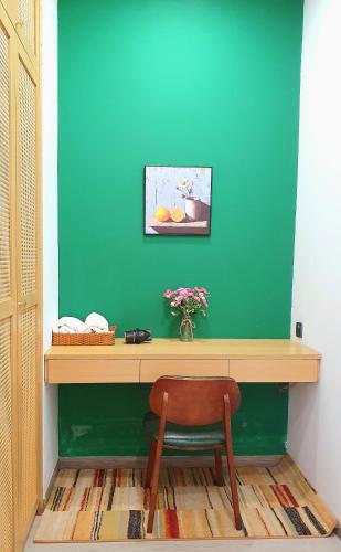 a desk with a chair in a room with a green wall at Andi Homestay-Vinhomes Grand Park in Gò Công