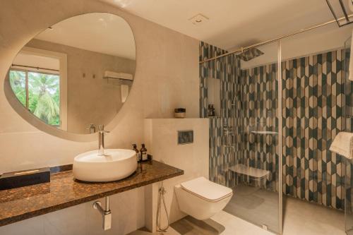 a bathroom with a sink and a toilet and a mirror at Kensho Marigold 3-BHK Villa Common Pool & Lift Beaches in Majorda