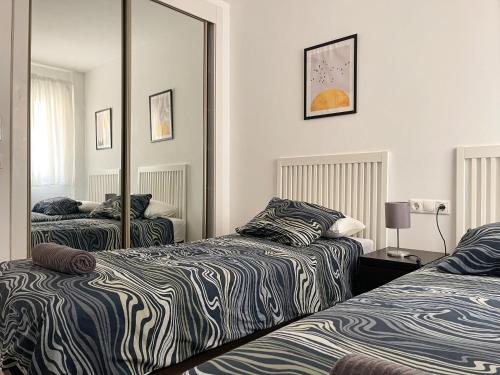 sypialnia z dwoma łóżkami i dużym lustrem w obiekcie DV Properties Residencial Apartment #P4F2 w Maladze