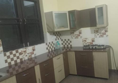 eine Küche mit braunen Schränken und Wandfliesen in der Unterkunft Chandra Leelas Ashirwad Cottage in Mukteswar