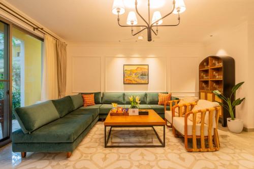 a living room with a green couch and a table at Kensho Marigold 3-BHK Villa Common Pool & Lift Beaches in Majorda