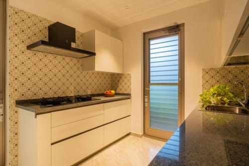a kitchen with white cabinets and a window at Kensho Marigold 3-BHK Villa Common Pool & Lift Beaches in Majorda