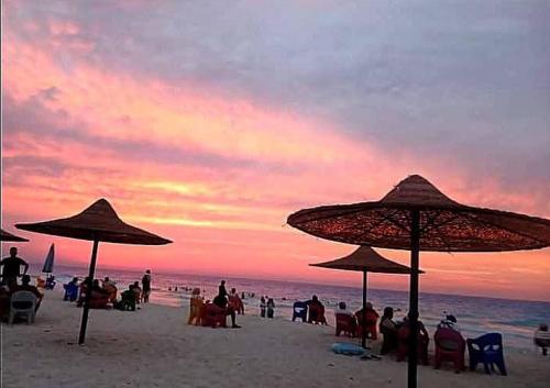 un groupe de personnes assises sur une plage avec des parasols dans l'établissement الصيف احلى فى الساحل, à El Alamein