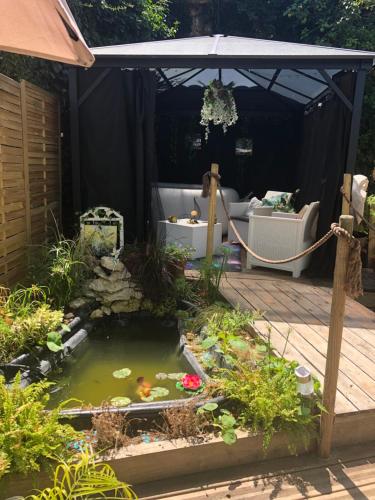 un bassin à carpes koï dans un jardin avec un parasol dans l'établissement l'Arche Enchantée, à Saint-Nicolas-de-la-Grave