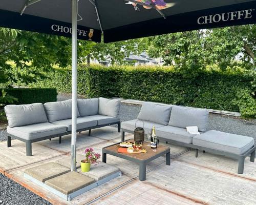 a group of couches and a table under an umbrella at Bonheur à la campagne in Bastogne