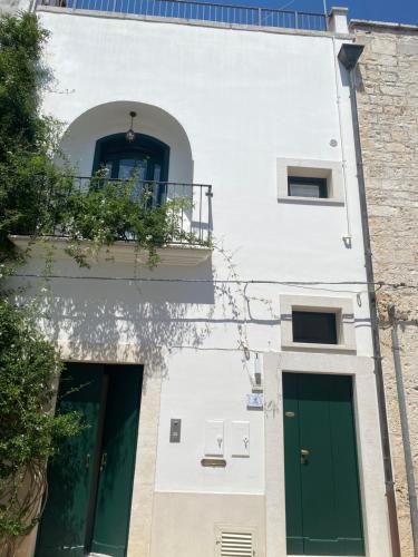a white building with green doors and a balcony at Dimora Violetta in Alberobello