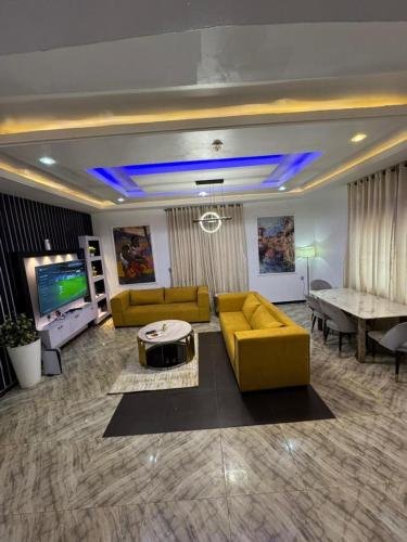a living room with a yellow couch and a table at Executive 4 Bedroom Bungalow at New Haven Extension, Enugu in Enugu