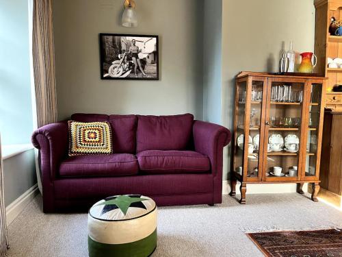 a living room with a purple couch and a table at Rooftops in Hay-on-Wye