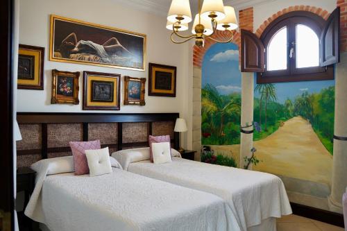 two beds in a room with a painting on the wall at Hotel Boutique Casa Veracruz in Estepona