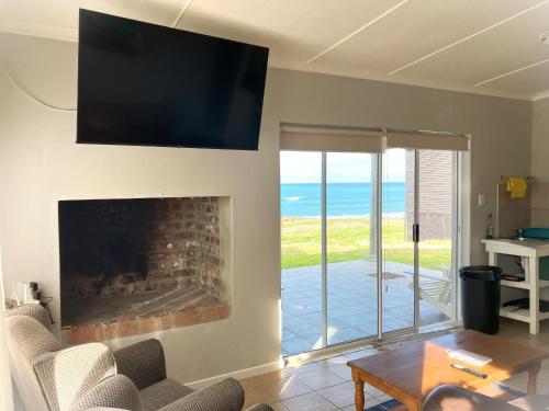a living room with a fireplace with a tv on the wall at Marine Magic in Struisbaai