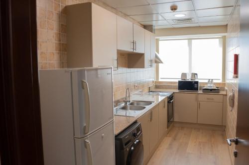 a kitchen with a refrigerator and a sink at Grand Millennium Dubai in Dubai
