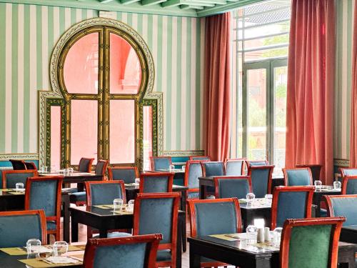 a dining room with tables and chairs and a window at Grand Mogador Agdal & Spa in Marrakech