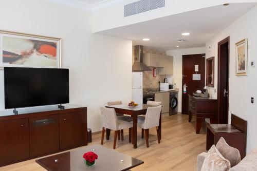 a living room with a television and a table with chairs at Grand Millennium Dubai in Dubai