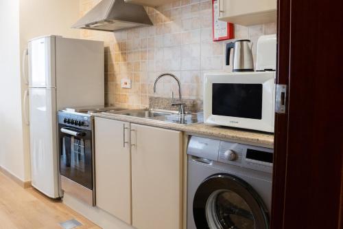a kitchen with a washing machine and a microwave at Grand Millennium Dubai in Dubai