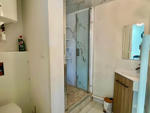 une douche avec une porte vitrée dans une salle de bain dans l'établissement Maisonnette, à 50m de la mer avec terrasse, à Luc-sur-Mer