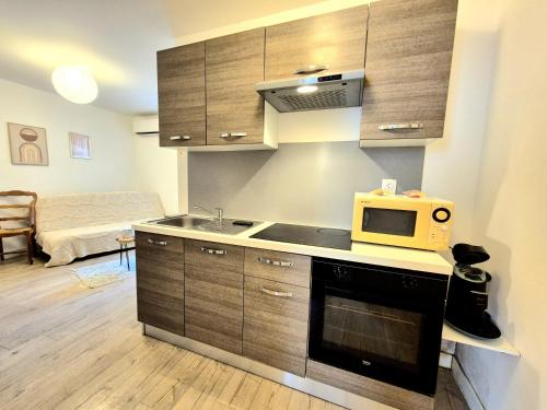 une cuisine avec un micro-ondes et une cuisinière four supérieur dans l'établissement La patio - coeur de ville - clim, à Nîmes