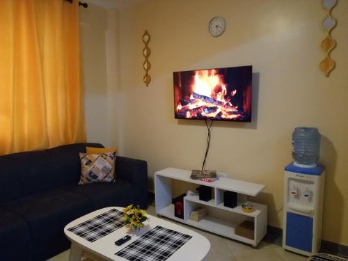 a living room with a couch and a tv on the wall at Ayo's Vacation Home in Thika