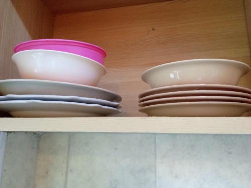 three bowls and plates sitting on a shelf at Ayo's Vacation Home in Thika