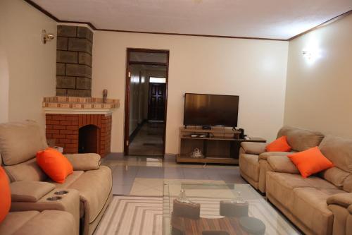a living room with two couches and a television at Axis Guest House in Syokimau