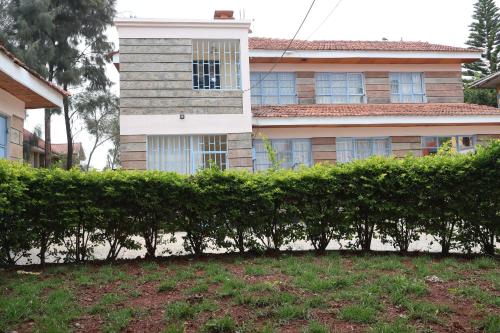 a house with a hedge in front of a building at Axis Guest House in Syokimau
