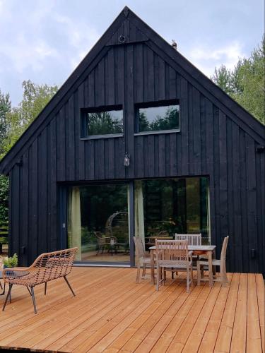 a black building with benches and a table on a deck at Domek W Konwaliach in Krutyń