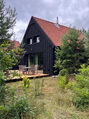 a black house with a table and chairs in a yard at Domek W Konwaliach in Krutyń