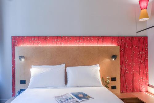 a bed with a red headboard with a book on it at Hotel Casa W in Venice