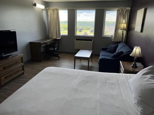 a bedroom with a bed and a couch and a television at Ramada by Wyndham Florenceville in Florenceville
