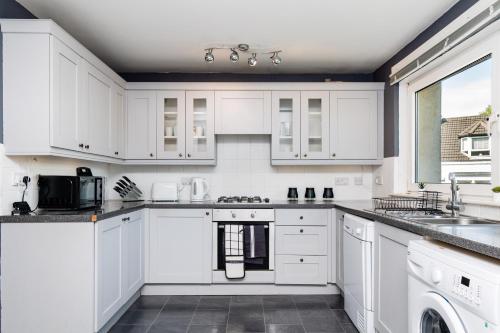 a white kitchen with white cabinets and appliances at 2 Bedroom Flat - Free Parking- by Holiday Homes in Clydebank