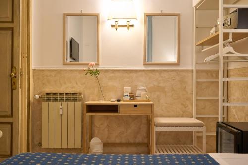 a room with a bed and a desk and a mirror at Hotel Ascot in Rome