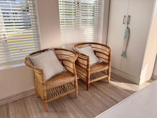 two wicker chairs in a room with a window at Keurbooms Getaway Studio in Plettenberg Bay