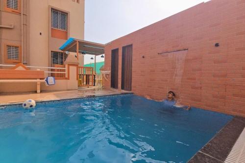 a woman in a swimming pool next to a brick building at Lux Pvt Pool, Rain Dance, Near Bhimashankar, Pets! in Manchar