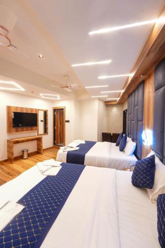 a hotel room with two beds and a flat screen tv at Hotel Prince Palace in Mumbai