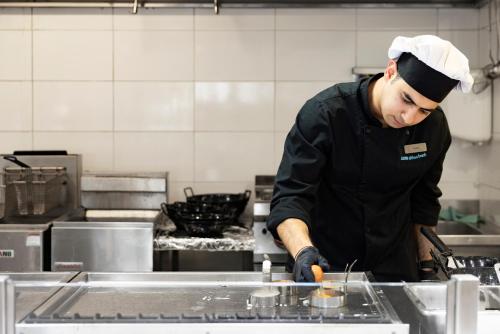 a chef preparing food in a kitchen at Louis Althea Beach in Protaras