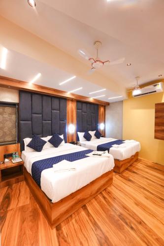 two beds in a room with wooden floors at Hotel Prince Palace in Mumbai