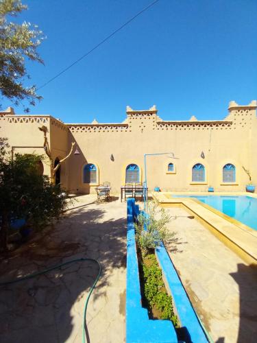 a building with a swimming pool in front of it at Maison Mirage B&B in Hassilabied