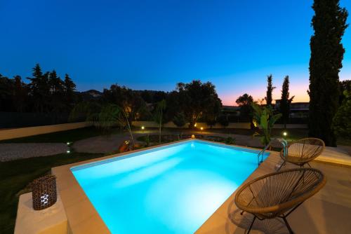 a swimming pool with two chairs next to it at SunnyVilla Rhodes in Ialysos